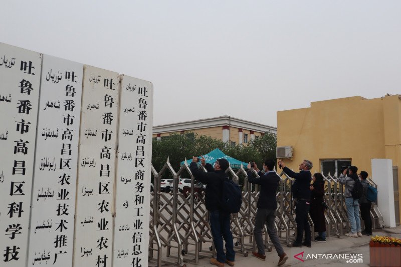 Several foreign journalists take pictures at a government office building in Xinjiang.